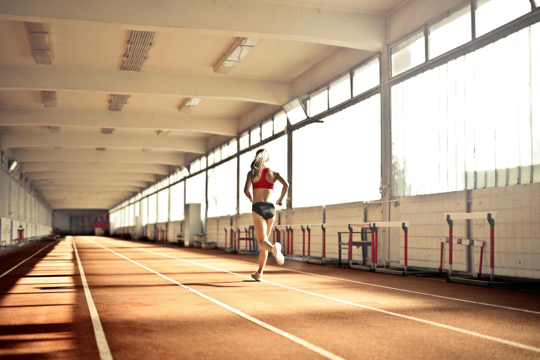 Biegaczka w stroju sportowym biegnie po krytej bieżni